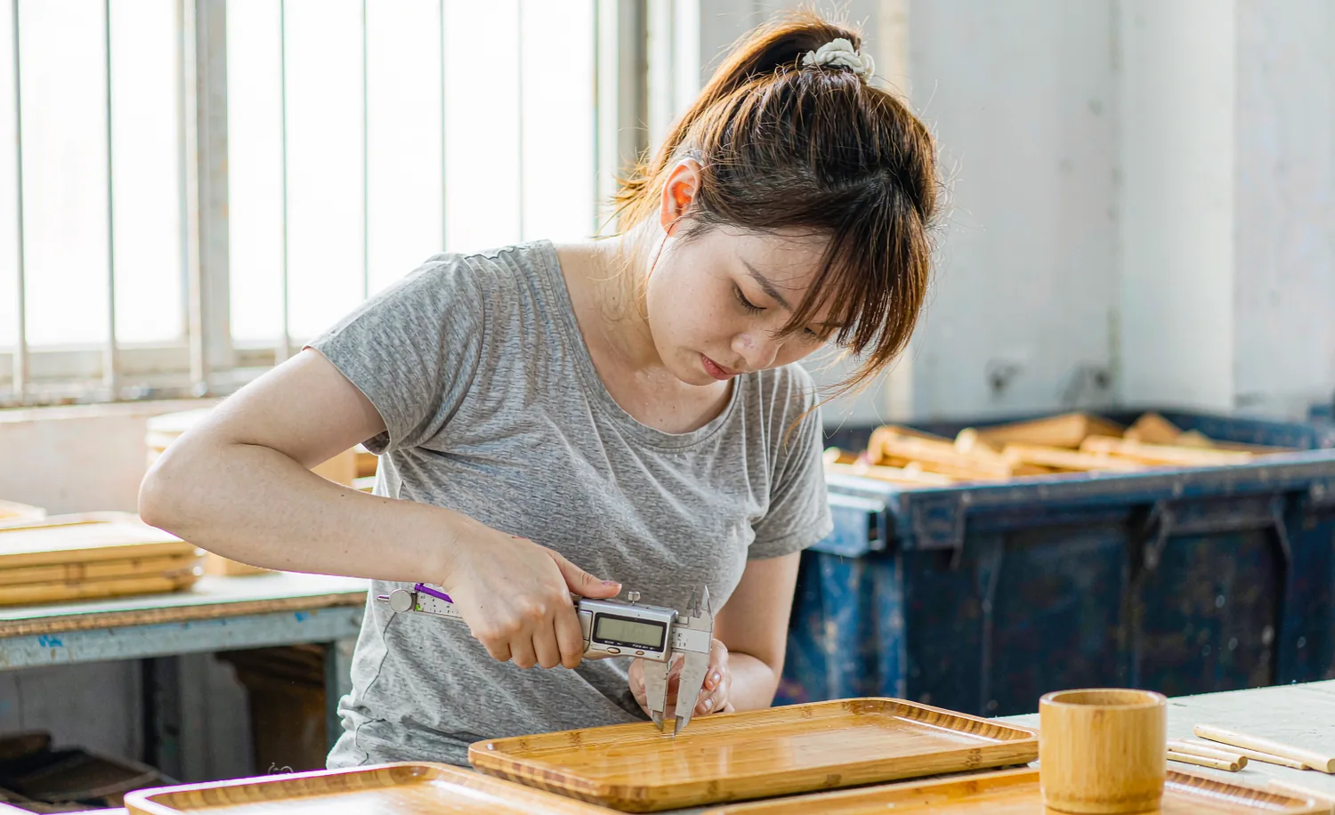 Craftswoman measuring a bamboo serving tray with a caliper
